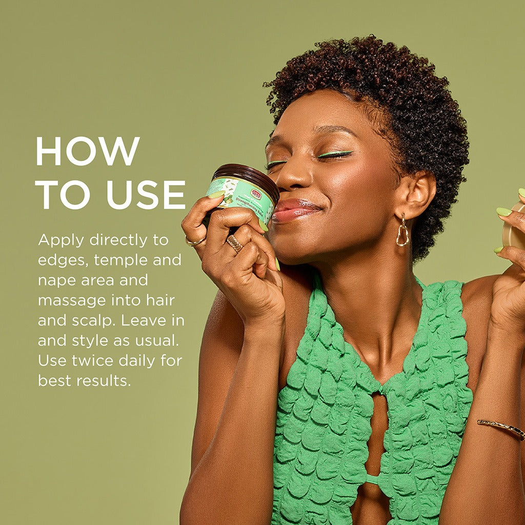 African Pride model holding jar and smelling peppermint rosemary strengthening hair balm while smiling