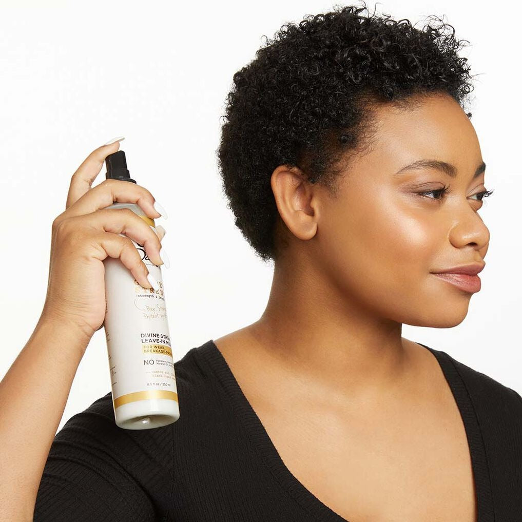 Woman with short curly hair spraying Carols Daughter leave-in milk for natural hair from bottle