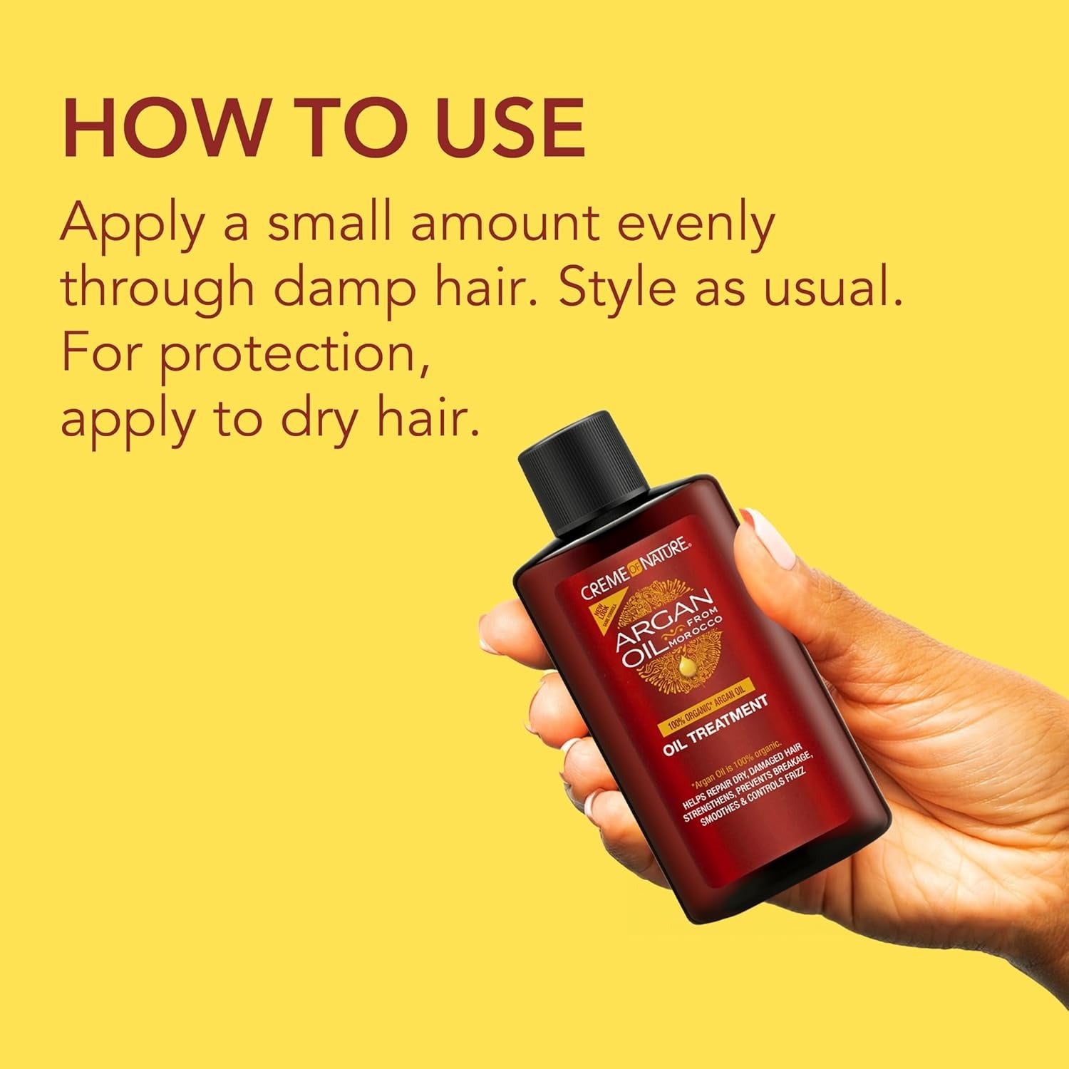 Hand holding Creme Of Nature Argan Oil Treatment bottle against yellow background with usage instructions for damp or dry hair