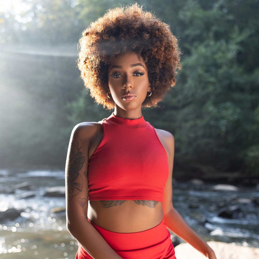 CREME OF NATURE sulfate free argan oil shampoo model with natural afro hair outdoors by a river wearing red crop top