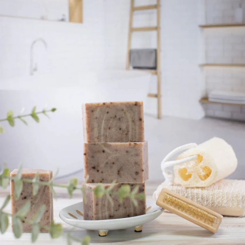 Earth to Me rosehip bar soap stacked on a dish with natural bathroom accessories in the background