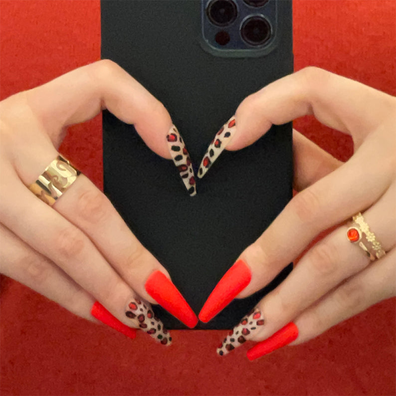 IVY BEAUTY by KISS leopard print press on nails long stiletto red matte and leopard accent manicure holding phone