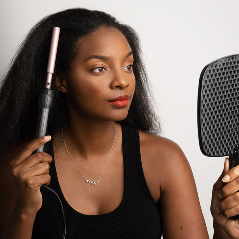 Woman styling natural hair with ANNIE digital ceramic pressing comb and a hand mirror for smooth sleek finish