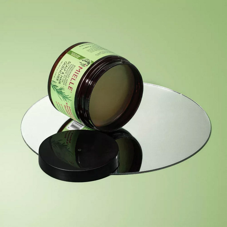 MIELLE rosemary mint hair pomade jar open on round mirror showing product texture