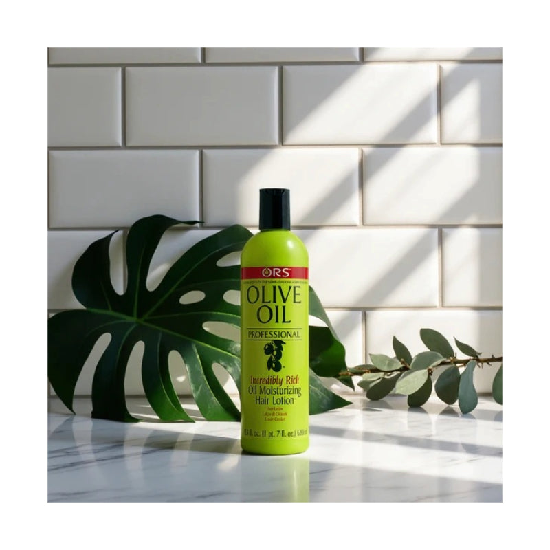 ORS Olive Oil Intensively Rich moisturizing olive oil hair lotion bottle on marble counter with monstera leaf