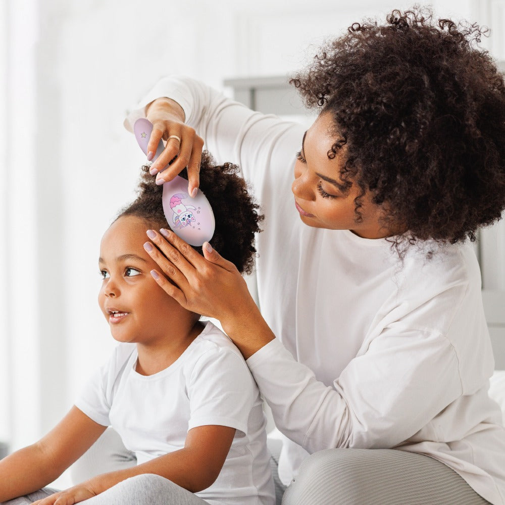 Mother using oval detangling hair brush on young girl with curly hair gentle styling by RED BEAUTY by KISS