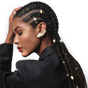Model with long braids adorned with gold rings shells and cuffs showcasing braid charm kit for hair styling