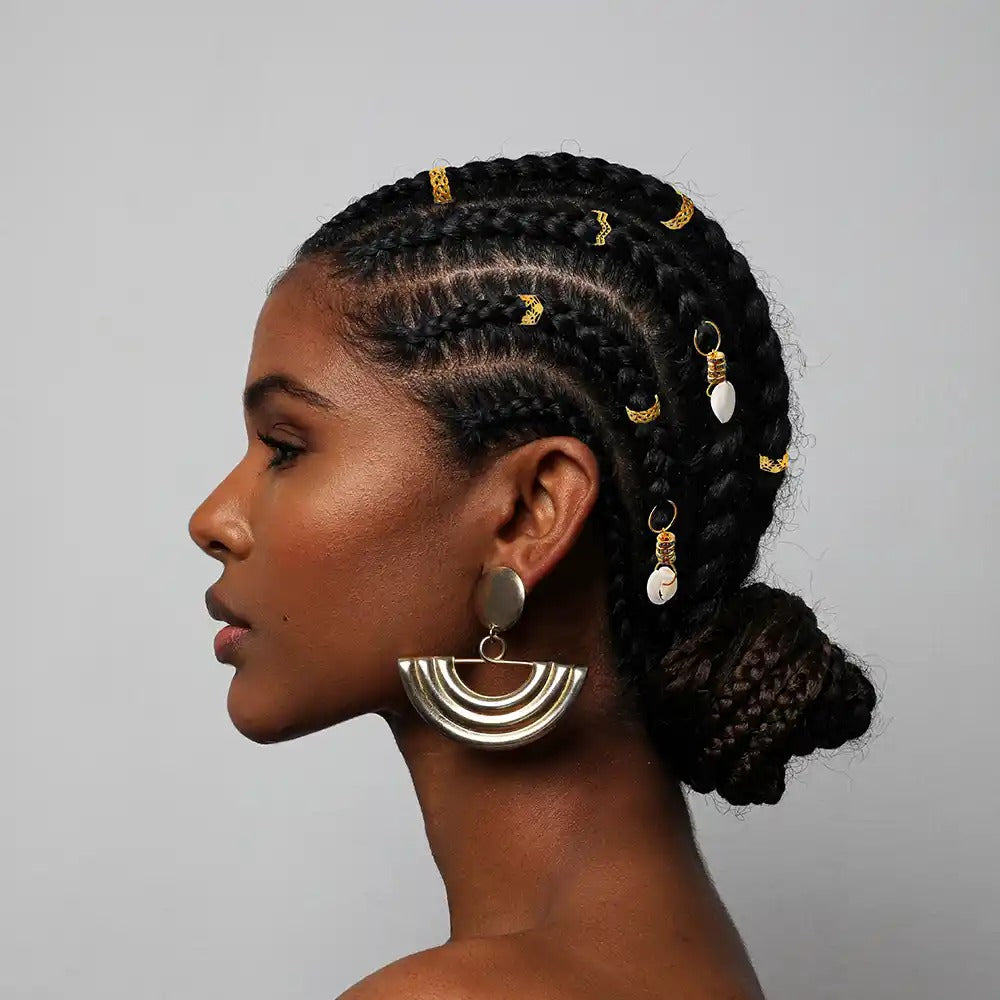 Side profile of woman with cornrow braids and gold shell accents wearing braid charm kit and large statement earring
