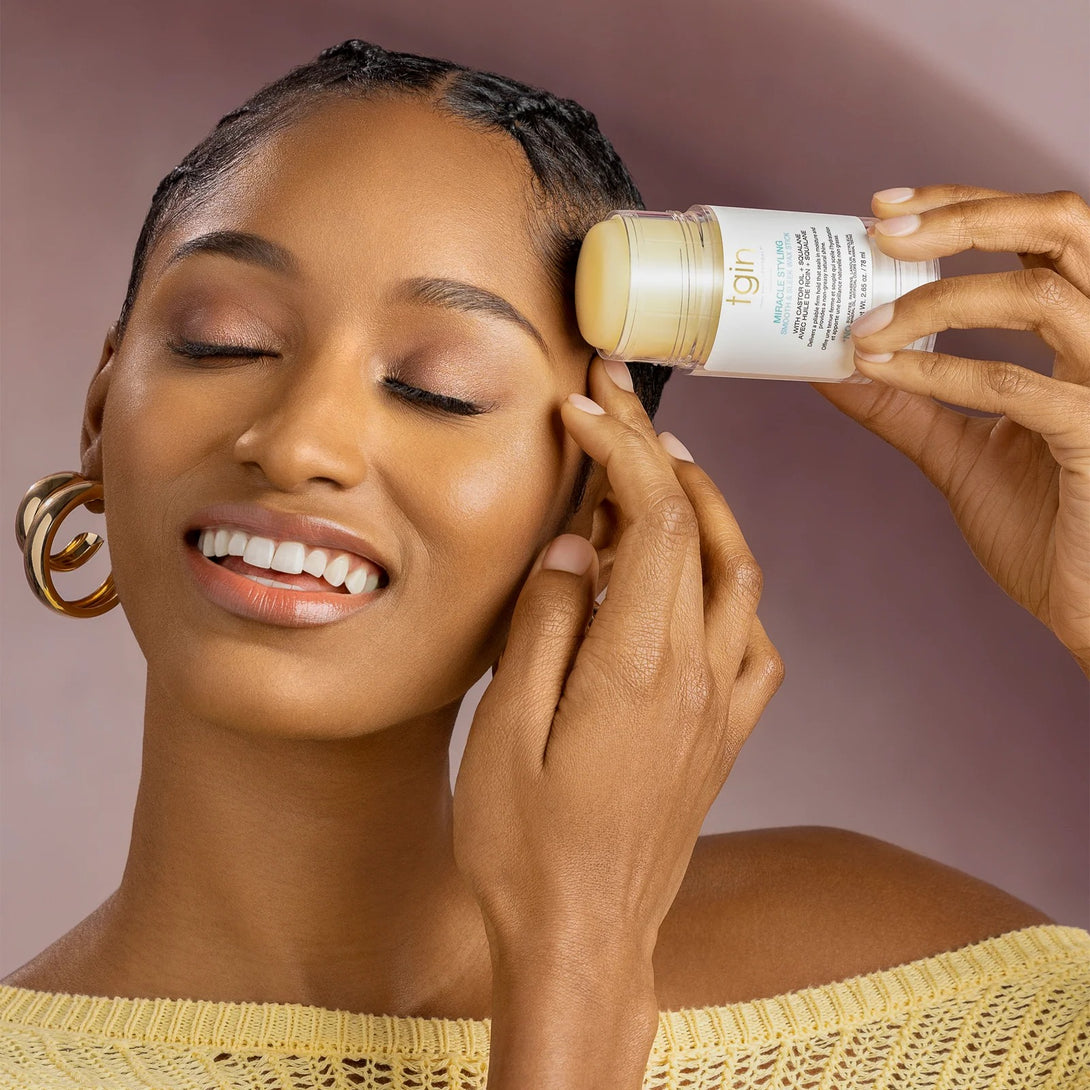 Model applying TGIN miracle hair styling wax stick to edges for sleek baby hairs and edge control