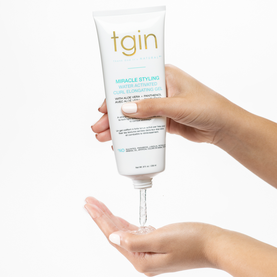 TGIN water activated curl gel being squeezed from white tube into hands for styling and elongating curls