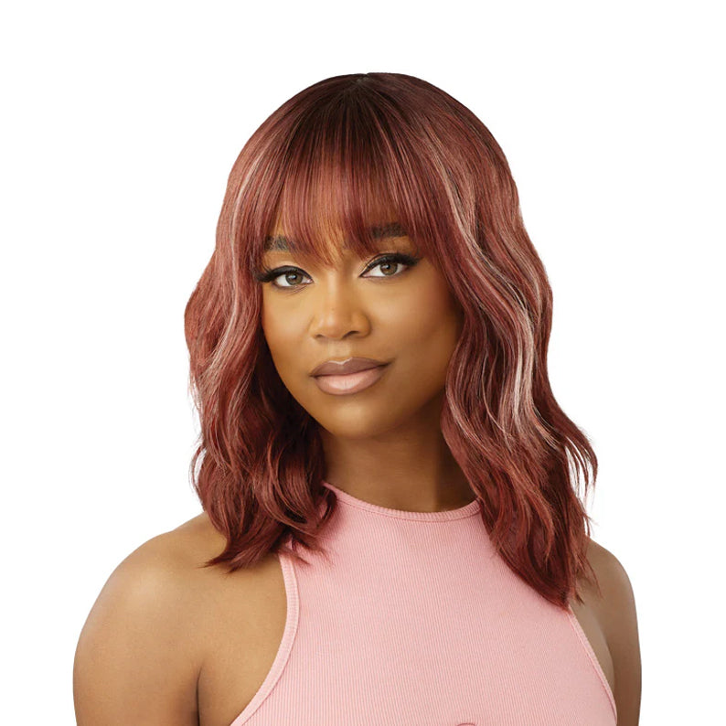 OUTRE synthetic hair wig 16 inch auburn wavy bob with bangs on model wearing pink tank top
